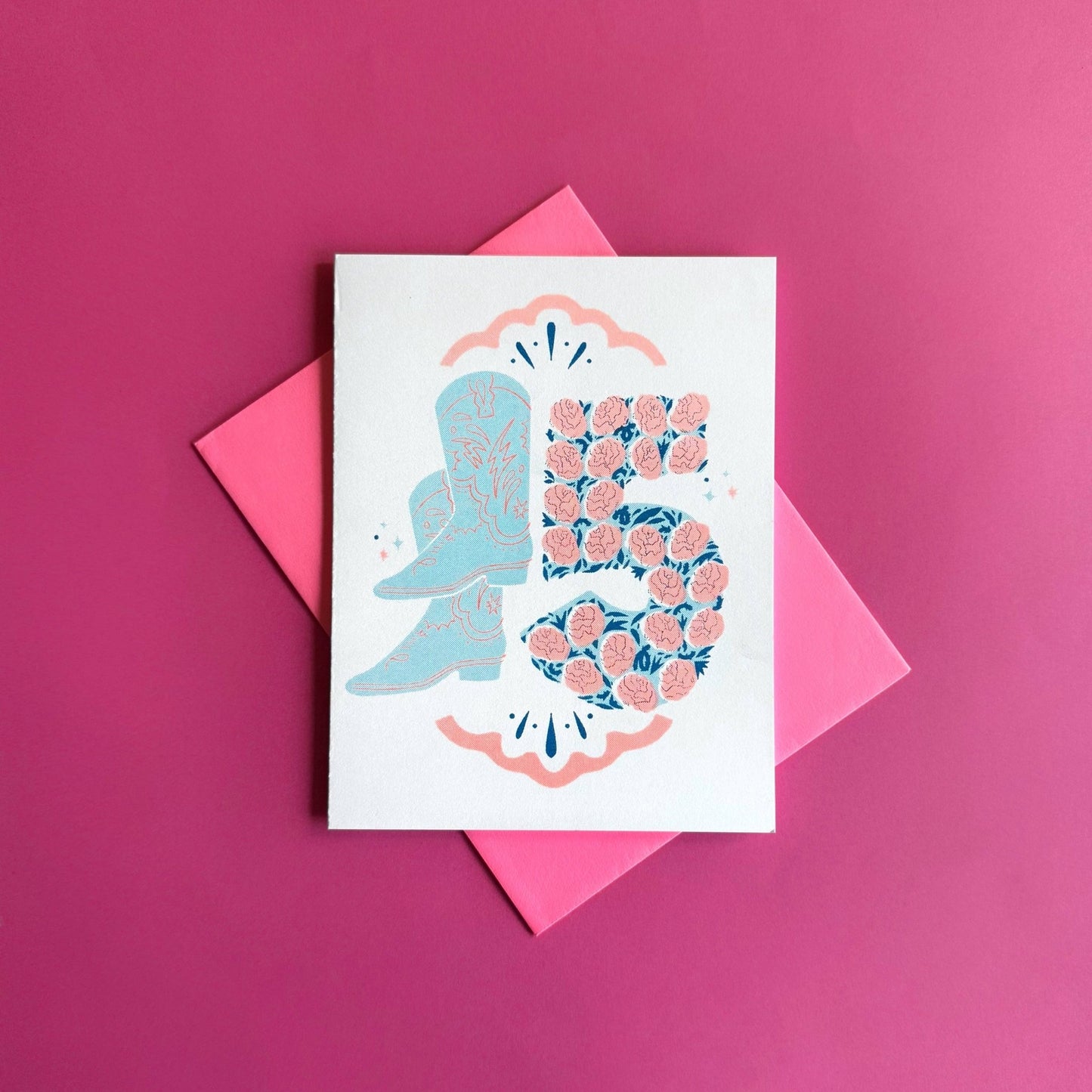Greeting card with a blue boot and pink floral design on a pink background