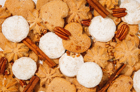 Assorted mexican heritage cookies with white mexican wedding cookies and cinnamon sticks surface