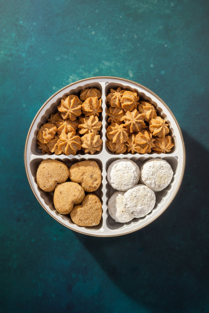 4 cavity cookie tin with three types of mexican cookies against a dark green background
