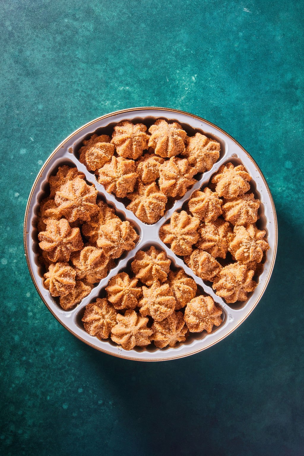 large stella cookie tin with churro cookies against a dark green background