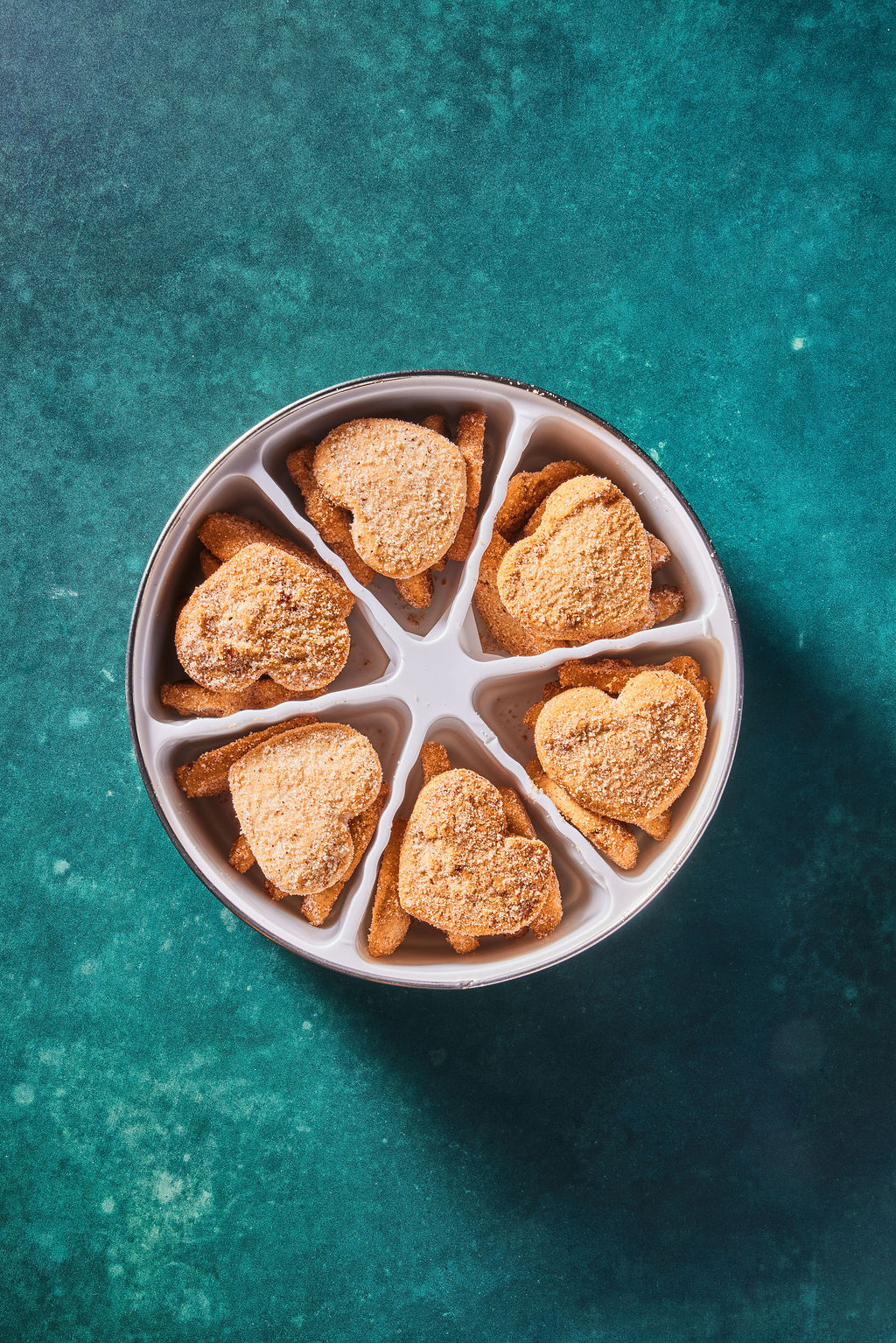 Heart-shaped cookies in a 6 plastic cavity on a teal background