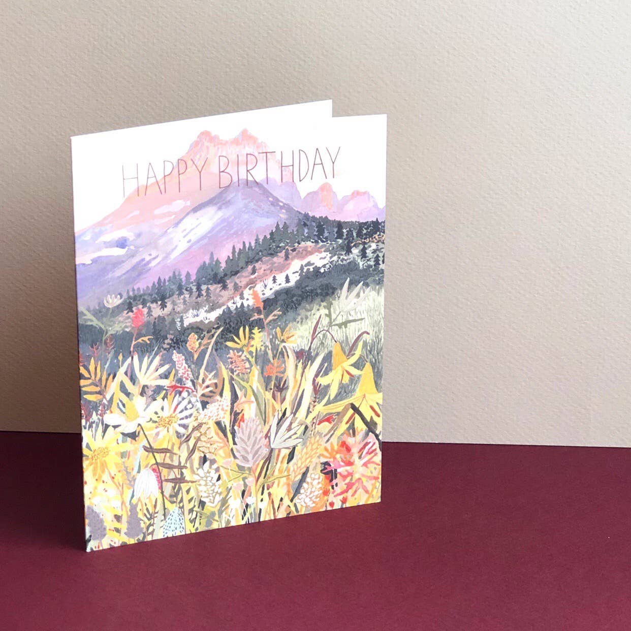 Greeting card with mountain and floral design on a plain background