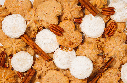 Assorted mexican heritage cookies with white mexican wedding cookies and cinnamon sticks surface