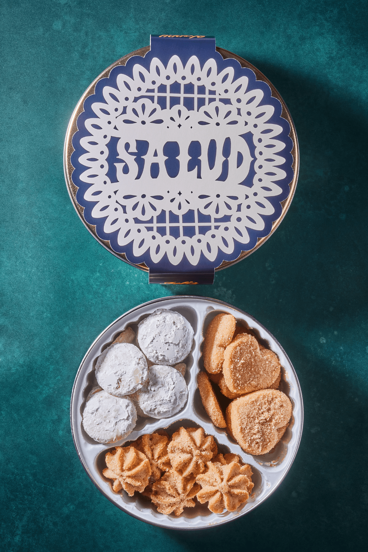 "Salud" cookie tin paper band that wraps around the cookie tin and a 3-partition variety cookie tin